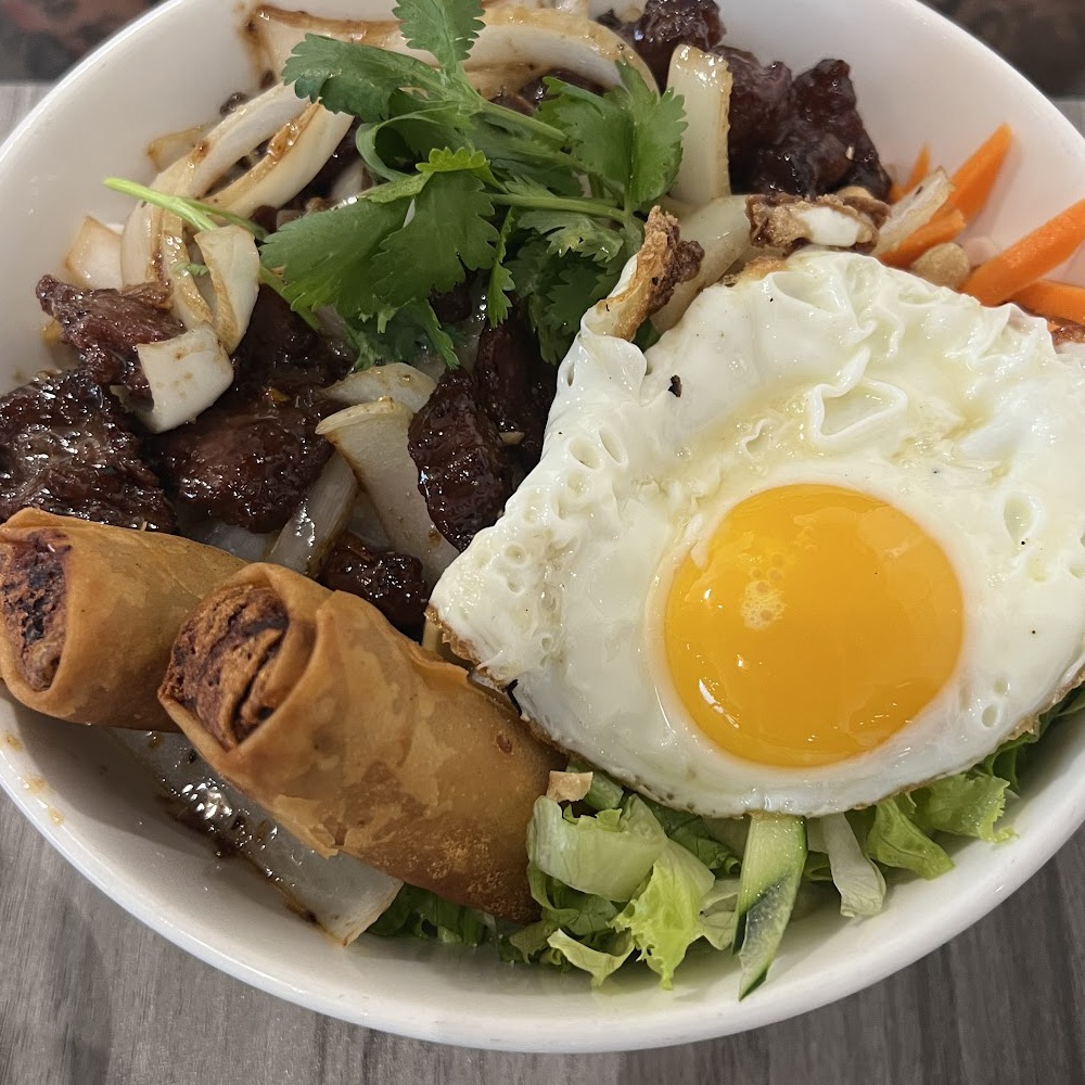 Signature rice bowl with spring rolls, grilled meat, and fried egg